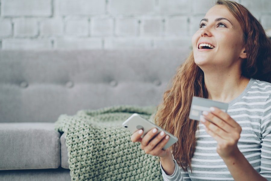 Lachende Kundin hält Smartphone und Bankkarte für die Prämieneinlösung